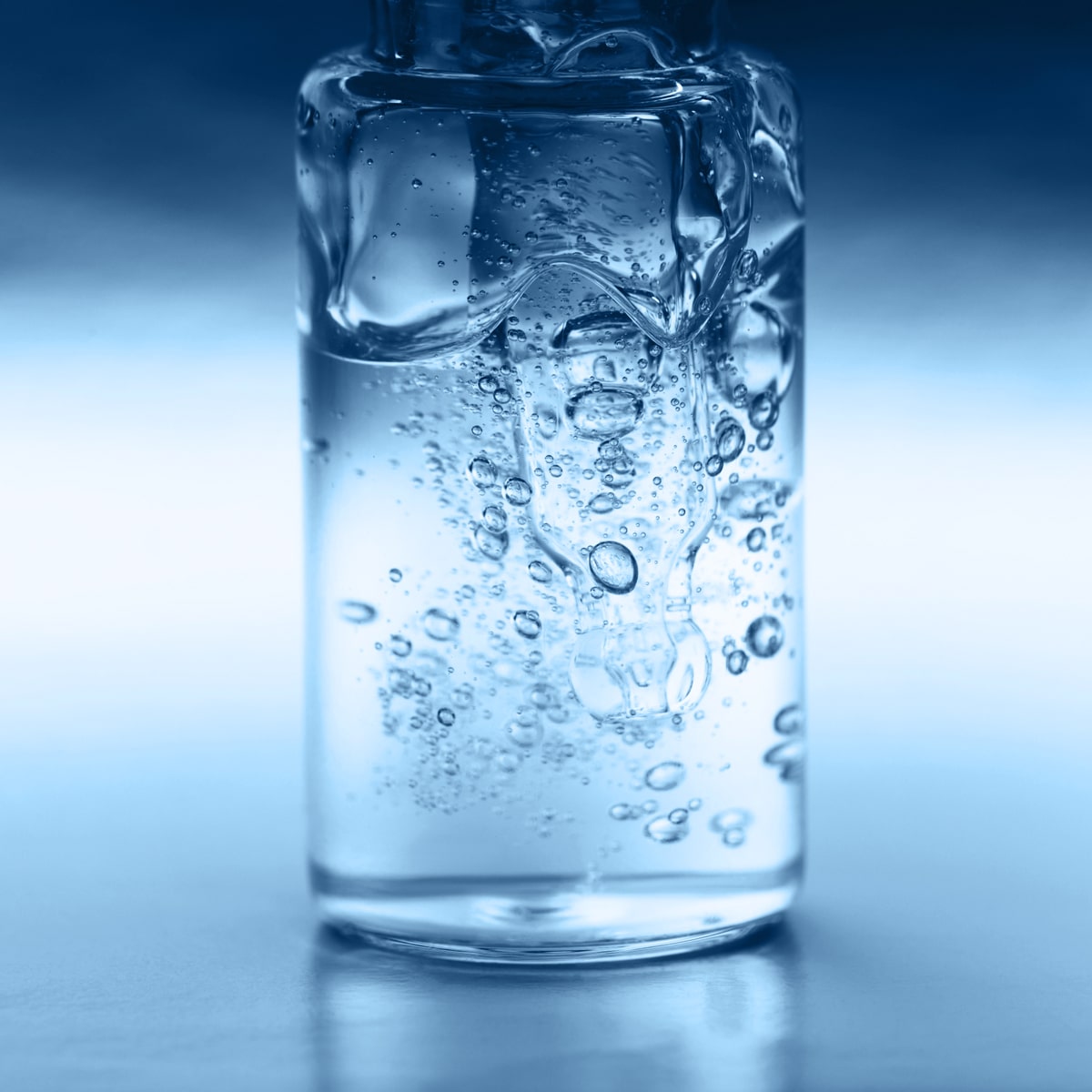 © Ortho Health Institut in München Eine Nahaufnahme einer durchsichtigen Flasche mit Wasser, die zahlreiche Luftblasen enthält, vor einem Hintergrund mit Farbverlauf in Blau. Das Bild, das an die gestochen scharfe Präzision erinnert, die das Ortho Health Institut so schätzt, fängt die feinen Details der Blasen ein und erzeugt so eine optisch ansprechende Textur.